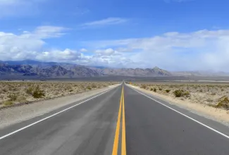 Driving on the open road in the desert with mountain backdrop